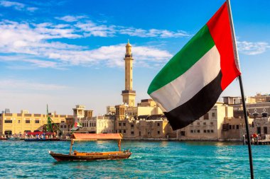 Abra 'ya karşı Birleşik Arap Emirlikleri bayrağına odaklan. Eski ahşap tekne ve Dubai Körfezi' ndeki Dubai Mescidi Camii.