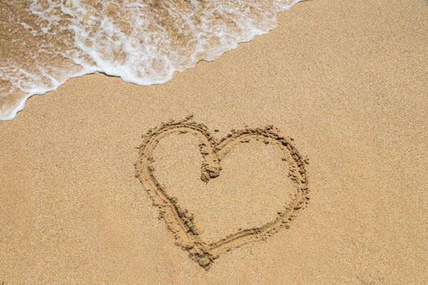 Символ сердца, написанный на песке на тропическом пляже