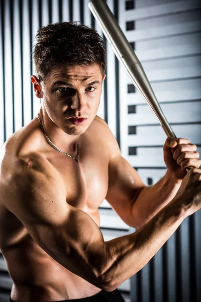 Muscular man posing with a bat — Stock Photo, Image