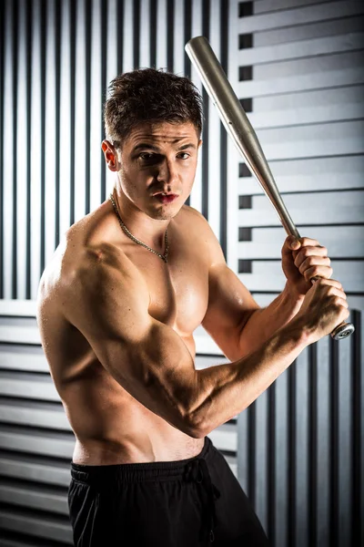 Muscular man posing with a bat — Stock Photo, Image