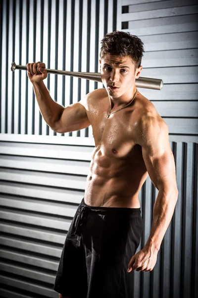 Muscular man posing with a bat — Stock Photo, Image