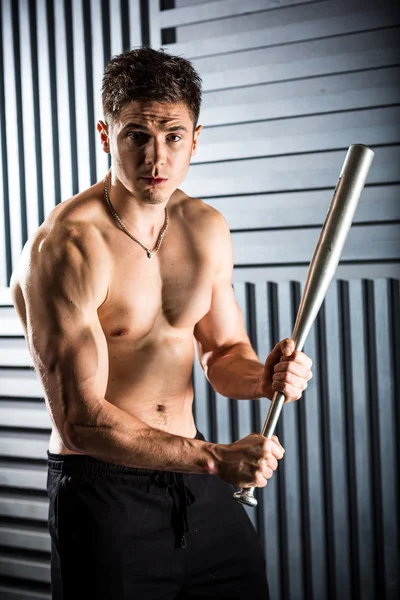 Muscular man posing with a bat — Stock Photo, Image