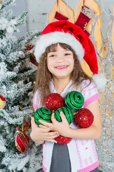 Liten flicka i santa hatt håller Juldekoration i händer — Stockfoto