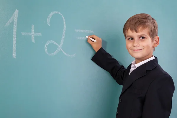 Schoolstudent schrijven op blackboard op school — Stockfoto