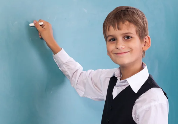 Estudiante de escuela escribiendo en pizarra en la escuela — Foto de Stock