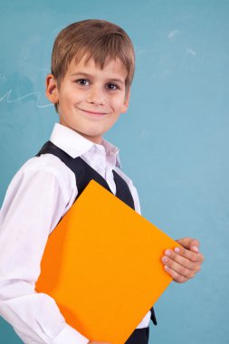 şirin bir okul çocuğu turuncu kitap tutuyor