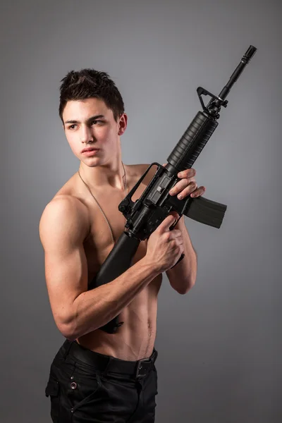 Handsome bare-chested soldier is holding a rifle — Stock Photo, Image