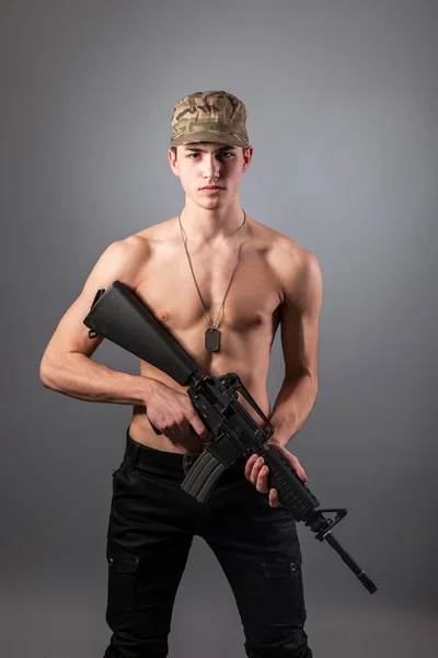 Handsome bare-chested soldier is holding a rifle — Stock Photo, Image