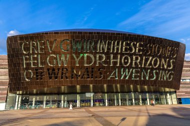 CARDIFF, İngiltere - 17 Haziran 2024: Galler Milenyum Merkezi 'nin günbatımında Cardiff, Galler' de ikonik iki dilli yazıtla dış görünümü, Birleşik Krallık modern kültürel simgesi