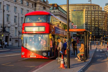 LONDON, İngiltere - 25 Haziran 2024: Yolcular İngiltere 'nin başkenti Londra' da Westminster Köprüsü yakınlarındaki St. Thomas Hospital County Hall durağında çift katlı kırmızı bir otobüse biniyor.
