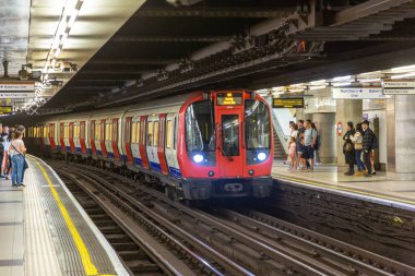 LONDON, İngiltere - 26 AĞUSTOS 2024: Londra Metro treni Embankment İstasyonu 'nda Londra, İngiltere, İngiltere' de bekleyen yolcularla birlikte