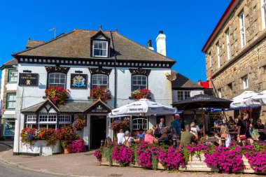 CORNWALL, İngiltere - 18 EPTEMBER 2024: Güneşli bir yaz gününde tarihi Marazion, Cornwall, İngiltere 'de açık hava oturma ve çiçeklerle geleneksel İngiliz barı