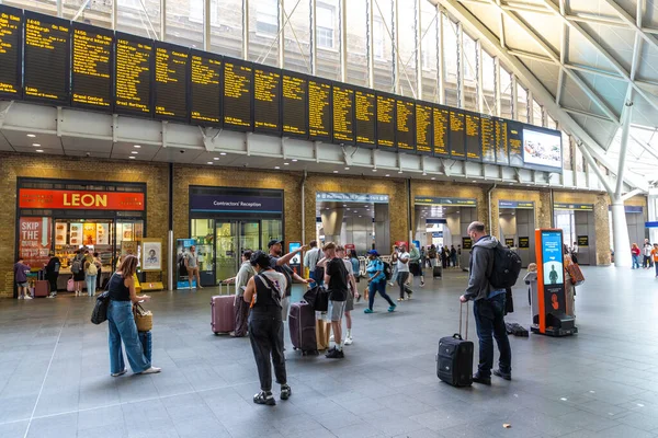 LONDON, İngiltere - 19 AĞUSTOS 2024: Londra, İngiltere 'deki Kings Cross tren istasyonunda tren kalkış panosuna sahip yolcular