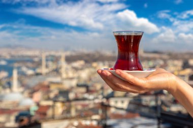 Kadın eli Türk çay fincanı ve İstanbul ve Türkiye 'nin panoramik hava manzarasını tutuyor