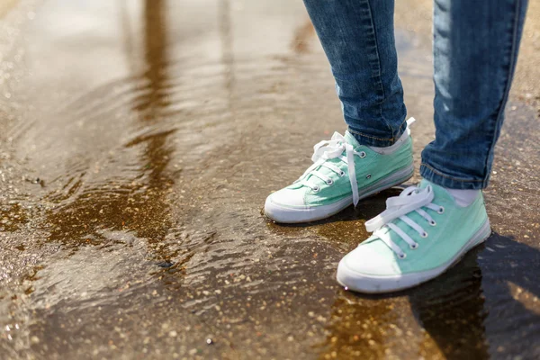 Kvinna i sport skor står i en vattenpöl — Stockfoto