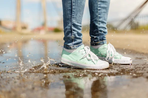 Femme en gomme sautant dans une flaque d'eau Image En Vente