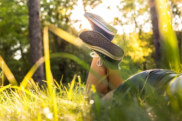 Liggande på en gräs i sneakers — Stockfoto