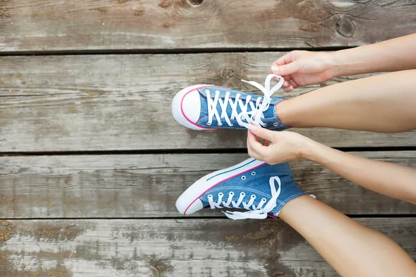 Attacher des lacets de baskets de jeans sur le sol en bois — Photo