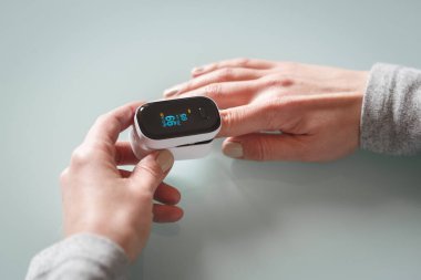 Kadın hastaların ellerinin, taşınabilir oksimetre kullanarak oksijen doygunluğunu ve nabzını ölçümlemesini yakından izleyin. Sağlık hizmeti kavramı