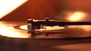 Closeup view of a tonearm and turntable playing vinyl record. Entertainment and music trends. Warm light color video