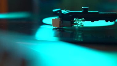 Closeup view of a tonearm and turntable playing vinyl record. Entertainment and music trends.Cold  blue light color video