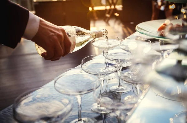 パーティーでスパークリングワインをグラスに注ぐウェイターの手の日没のクローズアップビュー ホスピタリティとケータリングサービスのコンセプト — ストック写真