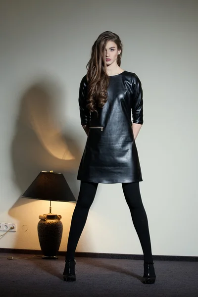 Jonge verleidelijke vrouw in een zwart lederen jurk — Stockfoto