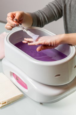 Female hands in a paraffin wax bowl clipart