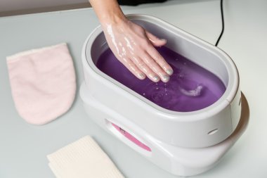 Female hands in a paraffin wax bowl clipart