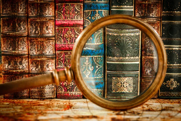 Ancient old books and magnifying glass — Stock Photo, Image