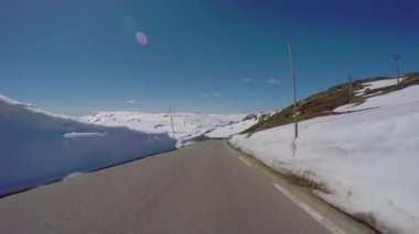 Norveç 'te yüksek kar duvarı olan bir dağ yolunda araba sürmek