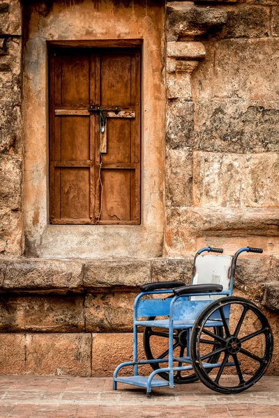 Wheelchair on a background of a stone wall — Stock Photo, Image