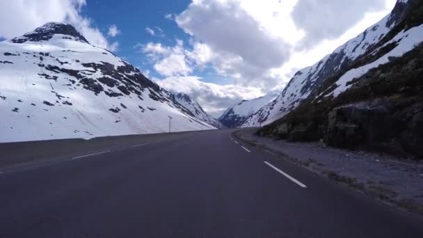 Автомобіль на гірській дорозі в Норвегії з високою сніговою стіною. — стокове відео