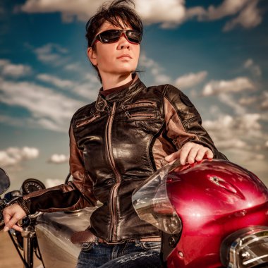 Motorcu kız bir deri ceket ve motosiklet üzerinde oturan güneş gözlüğü