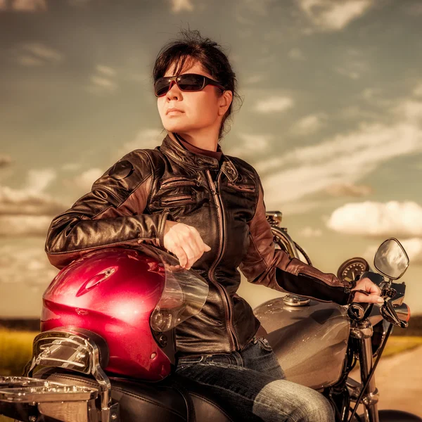 Chica motorista en una chaqueta de cuero y gafas de sol sentado en motocicleta — Foto de Stock