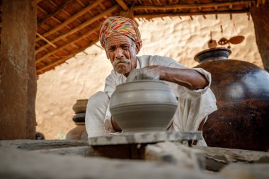 Potter iş yerinde seramik yemekler yapıyor. Hindistan, Rajasthan.