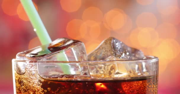 在模糊的灯光下 在模糊的背景下 在玻璃杯中加入冰块和气泡的可乐和饮料管 — 图库视频影像