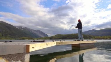 Norveç 'te balık oltasında dönen bir kadın. Norveç 'te balık tutmak yerel yaşam tarzını benimsemenin bir yoludur. Sayısız göl ve nehirler ve geniş bir kıyı şeridi olağanüstü fırsatlar demektir....