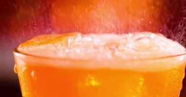 Bir bardak meşrubat. Su sıçratan köpüklü buzlu içecek bulanık bir ışıkta yavaş çekim, bulanık arkaplan.