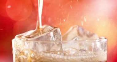 Bir bardak kola. Bulanık ışık ve bulanık arkaplan üzerinde su sıçratan baloncuklu buzlu kola yavaş çekim.