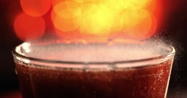 Bulanık ışık, bulanık arkaplan üzerinde yavaş çekimde su sıçratan baloncuklu kola.