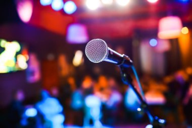 Sahnedeki halka açık gösteri mikrofon sahnesinde konser salonunun arka planına karşı. Yüzeyin derinliği. Sahnede halk gösterisi.