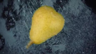 Siyah arka planda berrak su sıçraması olan armut. Süper Yavaş Hareket Döngüsü.