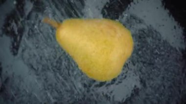 Siyah arka planda berrak su sıçraması olan armut. Süper Yavaş Hareket Döngüsü.