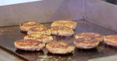 Et köftesi sıcak bir kızartma tavasında pişirilir. Sokak yemekleri, şef spatulayla hamburger çeviriyor..