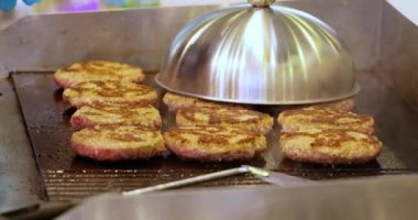 Et köftesi sıcak bir kızartma tavasında pişirilir. Sokak yemekleri, şef spatulayla hamburger çeviriyor..