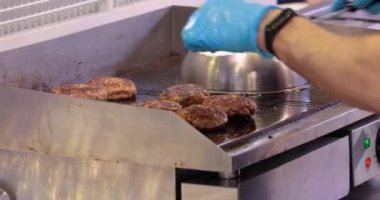 Et köftesi sıcak bir kızartma tavasında pişirilir. Sokak yemekleri, şef spatulayla hamburger çeviriyor..