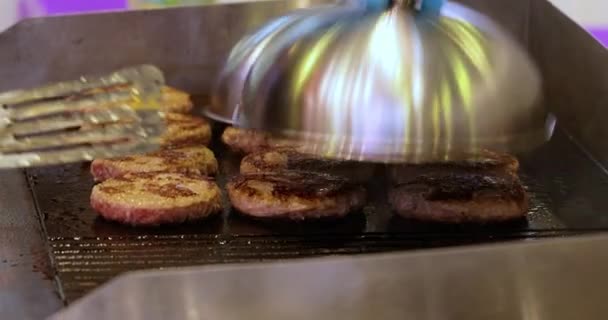 A húspástétomot forró serpenyőben sütik. Utcai ételek, séf feldobja hamburgerek spatula.