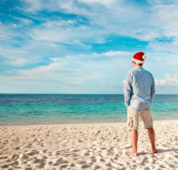 Człowiek w santa hat na tropikalnej plaży — Stockfoto