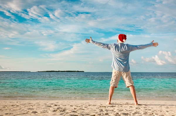 Człowiek w santa hat na tropikalnej plaży — Zdjęcie stockowe